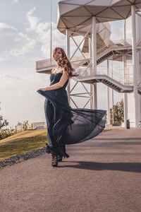 Full length of young woman with umbrella against sky