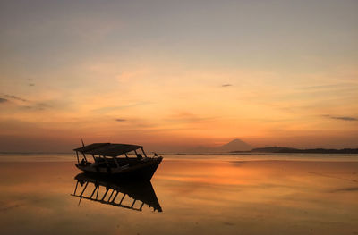 Boat at beach against sky during sunset