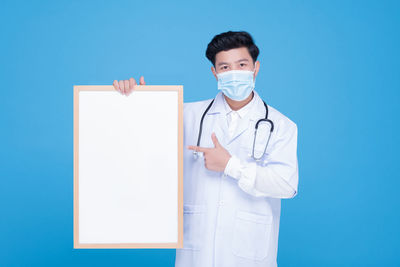 Portrait of man standing against blue background