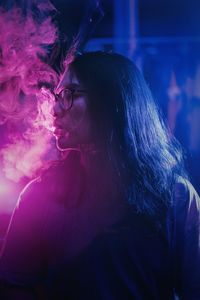 Man exhaling smoke in darkroom