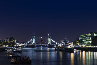 Illuminated bridge over river against sky at night