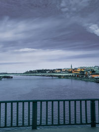 View of river by buildings against cloudy sky