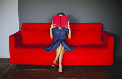 Beautiful young woman holding book sitting on sofa