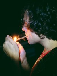 Close-up of man igniting cigarette at night