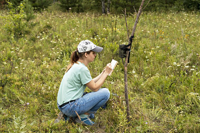 Woman scientist writing down data from trap camera to notepad,  reserve monitoring of rare animal 