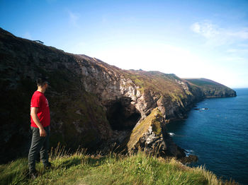 Man standing on mountain by road against sky