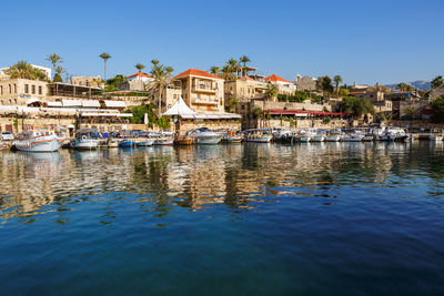 Sailboats moored at harbor against clear sky