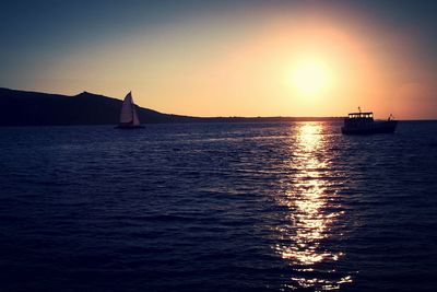 Sailboat sailing in sea at sunset