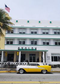 Yellow car on street against buildings in city