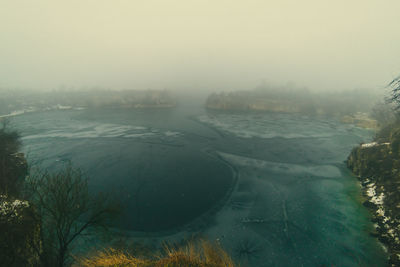 Scenic view of frozen landscape against sky during foggy weather