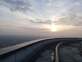 Bridge over road against sky during sunset