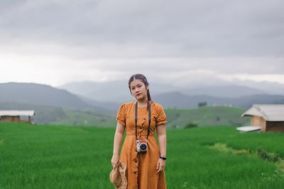 Portrait of young woman standing on landscape against sky