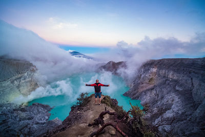 Man standing on rock against sky