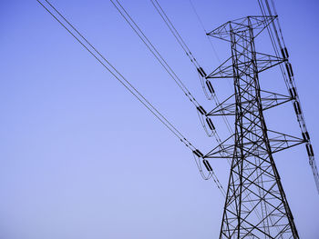 Low angle view of electricity pylon against clear blue sky