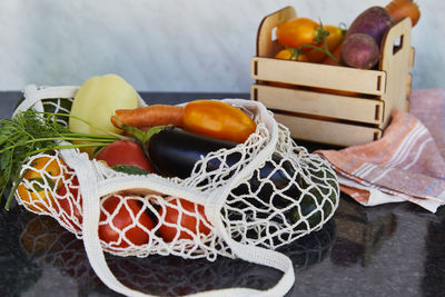 Seasonal vegetables in eco reusable bag and wooden box tomatoes, purple potatoes, eggplants, carrots