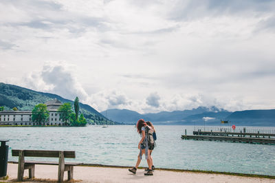 Women walking by sea against sky