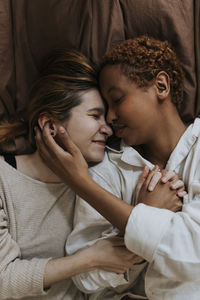 Directly above shot of non-binary couple lying on bed at home