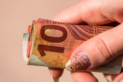 Close-up of hand holding paper over white background