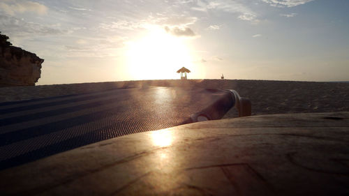 Low section of men on beach against sky during sunset