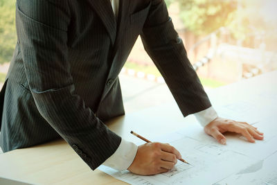 Midsection of businessman preparing blueprint