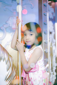 Portrait of cute girl sitting on carousel at amusement park