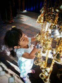 Full length of girl playing with bells hanging at shop