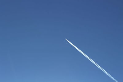 Low angle view of vapor trail against clear blue sky