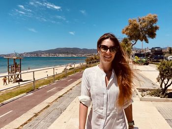 Portrait of young woman standing against sea