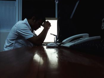 Side view of a young man sitting on table