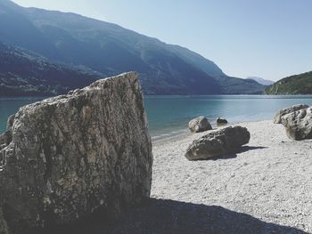 Scenic view of sea by mountains against clear sky