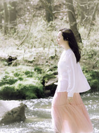 Rear view of young woman standing at lakeshore