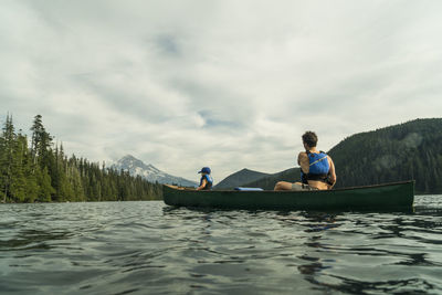 A young girl rides in a canoe with her dad on lost lake in oregon.