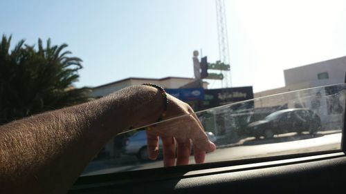 Close-up of man driving car on road against clear sky