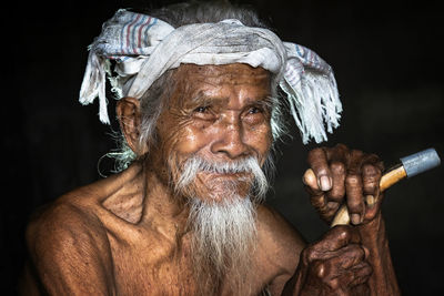 Close-up portrait of shirtless man against black background