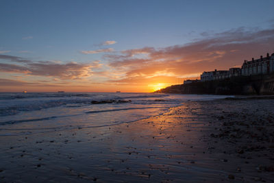 Beach against cloudy sky at dusk