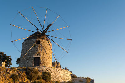 Low angle view of traditional windmill against clear blue sky