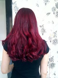 Rear view of young woman standing against wall