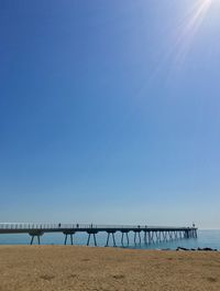 Bridge over sea against clear blue sky