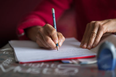 Cropped hands of woman writing in book