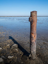 Rusty metal on beach against sky