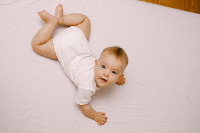 High angle portrait of cute baby lying on bed