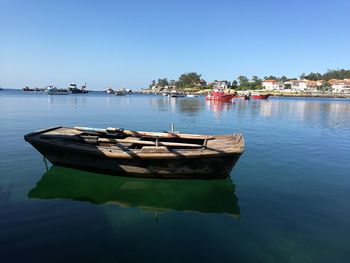 Boats in calm sea against clear sky