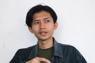 Portrait of young man standing against wall