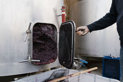 Man opening storage tank filled with crushed grapes