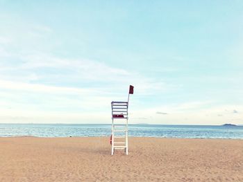 Lifeguard chair at beach against sky
