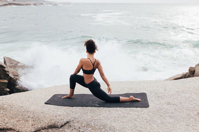 Full length of young woman exercising at beach