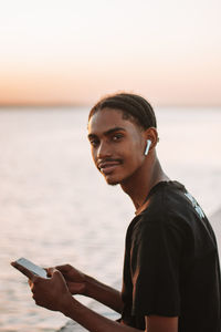 Portrait of young man using mobile phone at beach