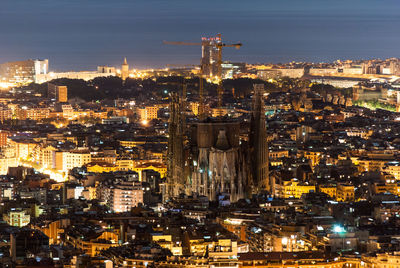 Sagrada familia amidst illuminated cityscape at night