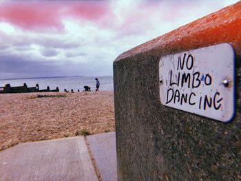 Information sign on beach against sky