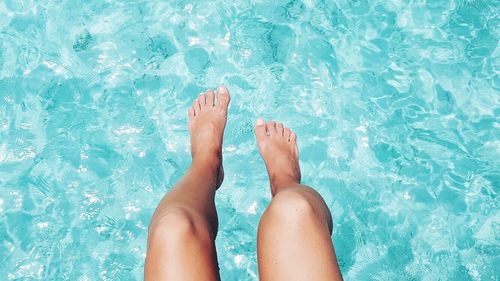 Low section of woman legs in swimming pool